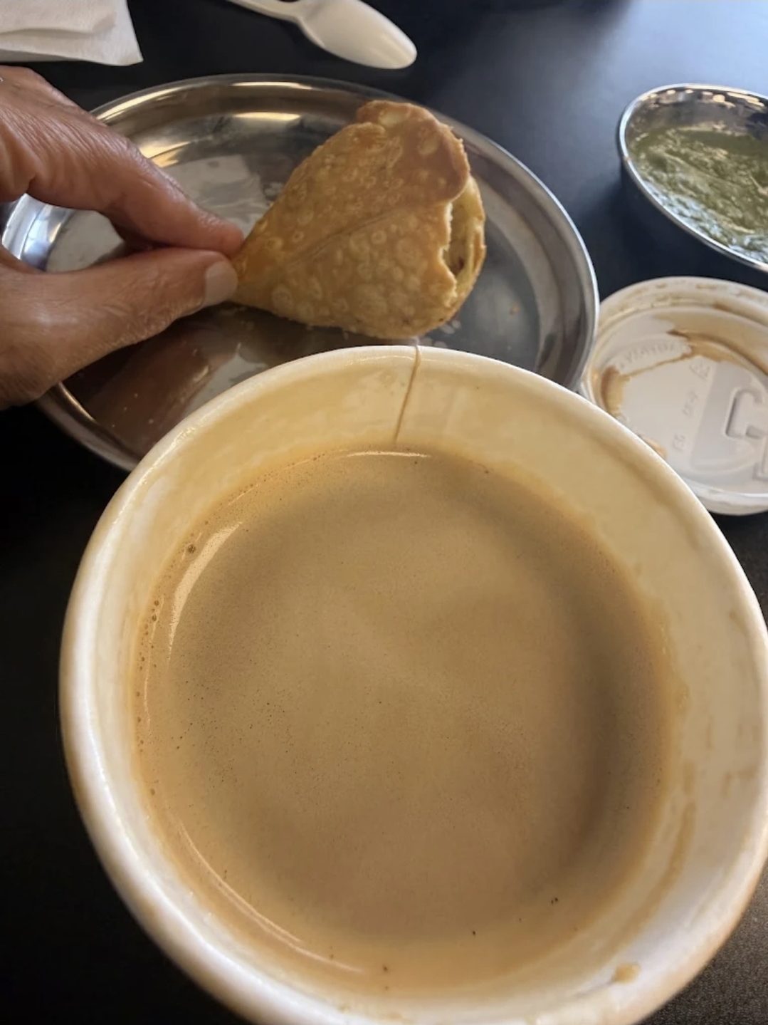 A samosa being dipped into a hot drink