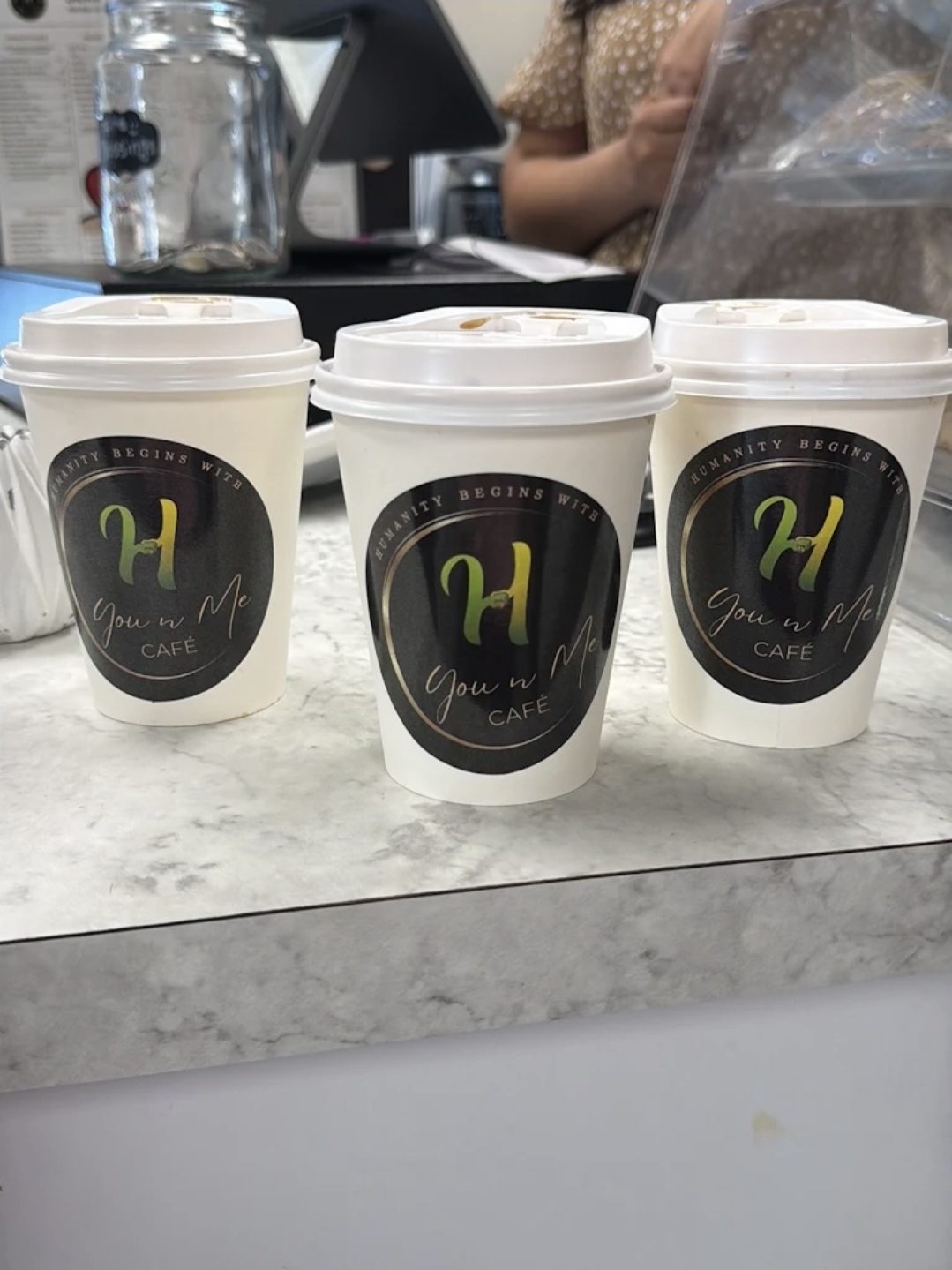 Three You N Me' takeaway cups on the counter