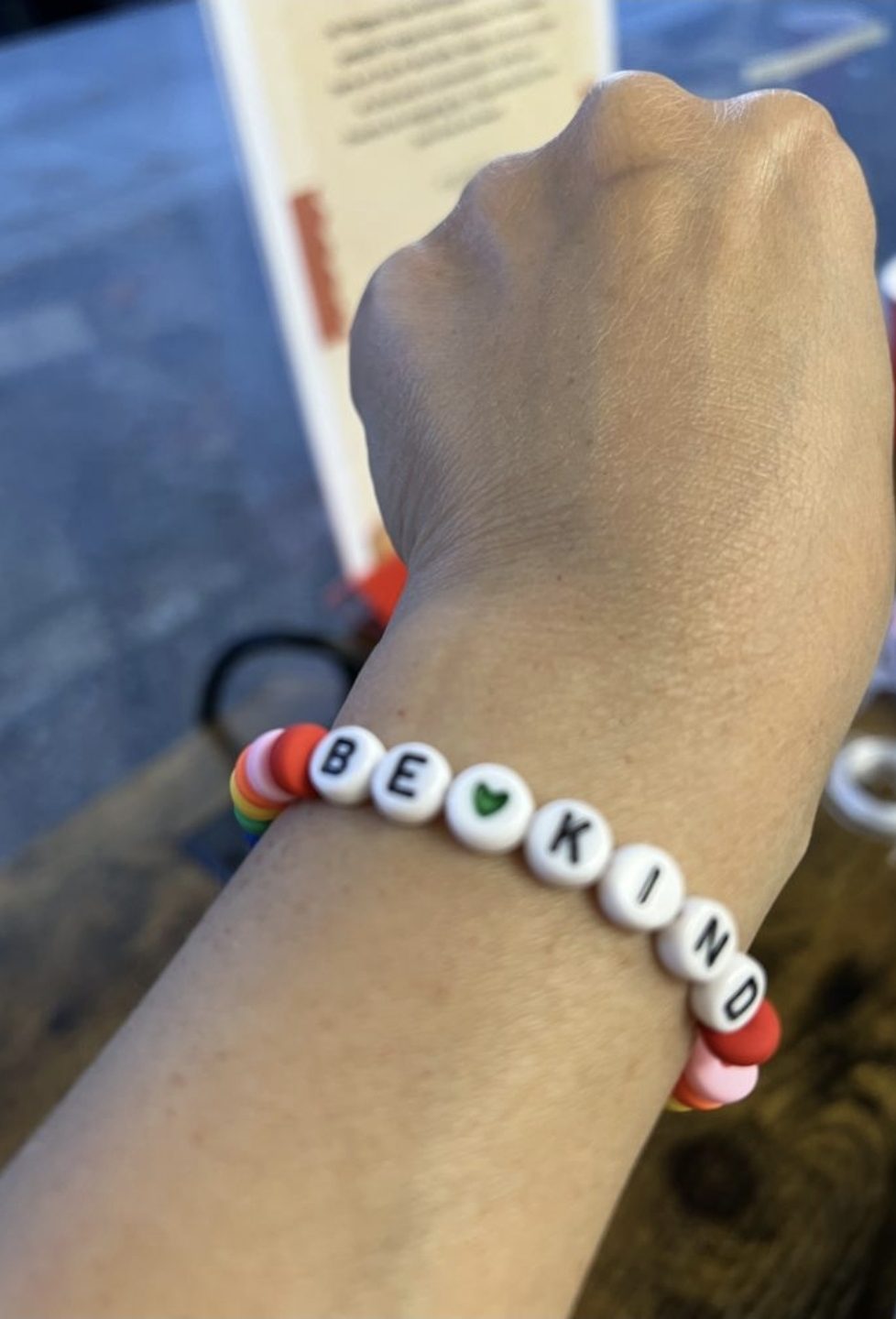 A beaded 'be kind' bracelet on a guest's wrist