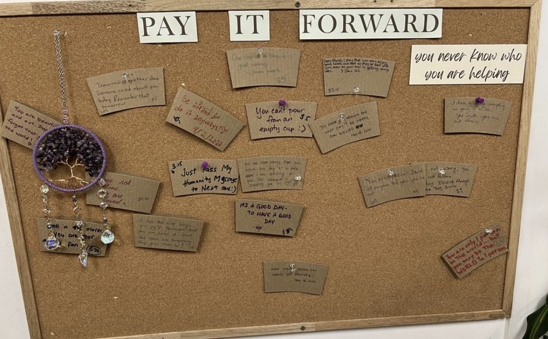 The Pay It Forward board, covered in handwritten notes from guests