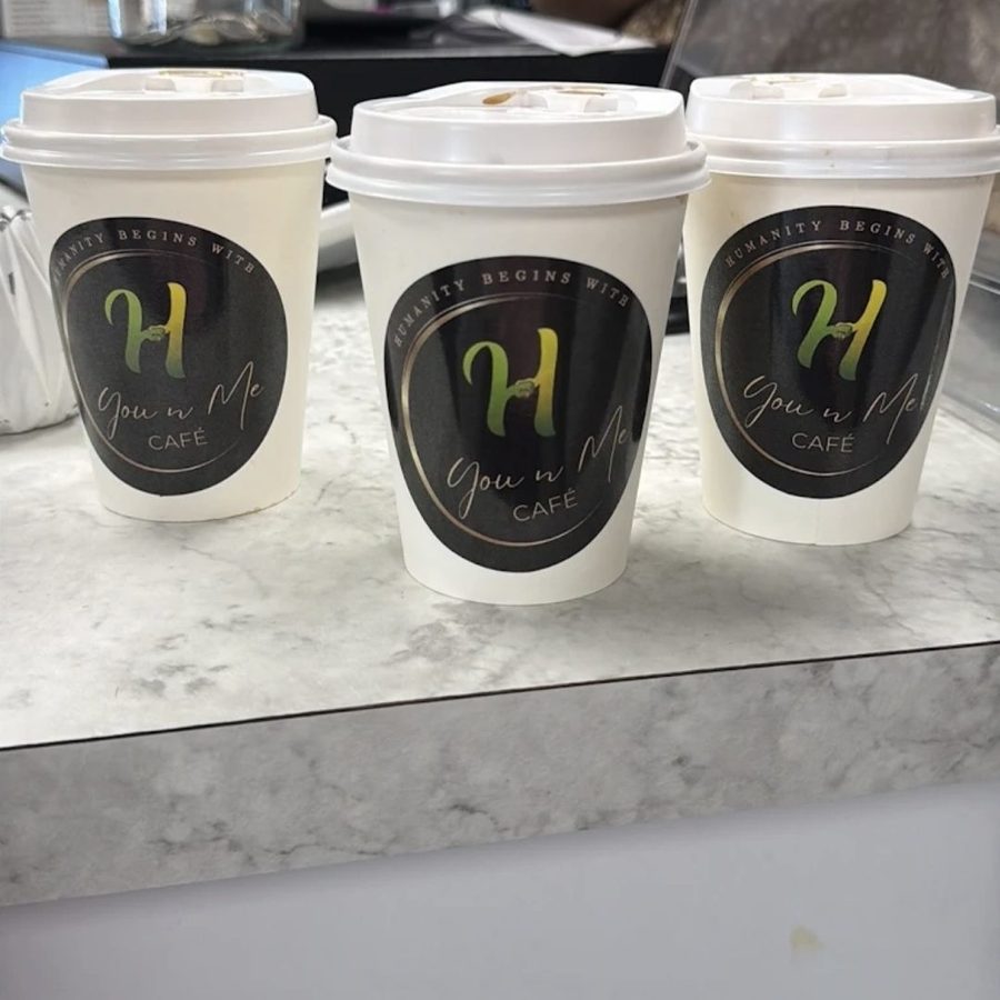 Three You N Me' Café takeaway cups with the Humanity Begins With You N Me' label